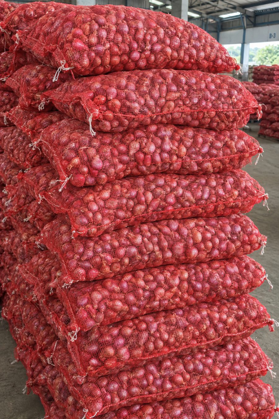 Stack of red mesh bags filled with shallots